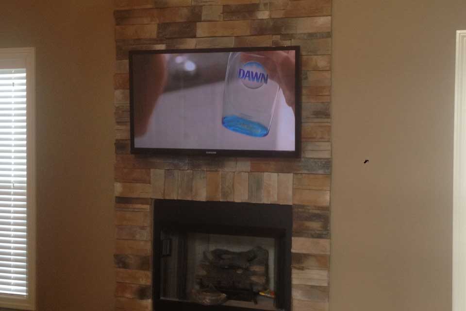 tv mounted over stone fireplace