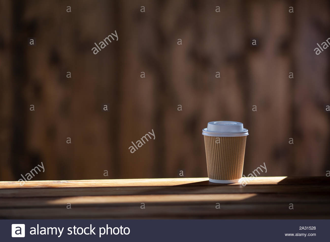 a cardboard cup for take away drinks standing on the wooden table on a wooden background 2A