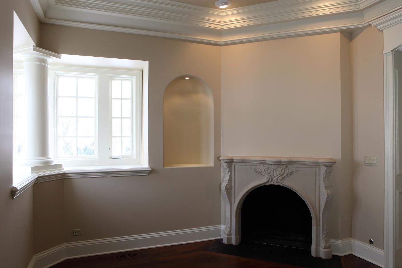 cream wall design with white accent and flat crown molding idea with glass wall and arched fireplace