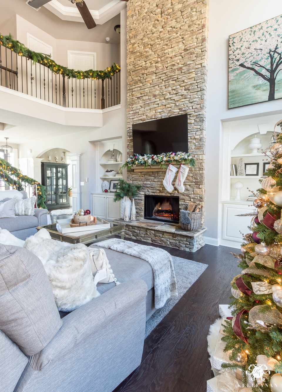 21 Beautiful Ways to Decorate the Living Room for Christmas two story living room with stacked stone fireplace 5b7b6c5046e0fb0082f9657f