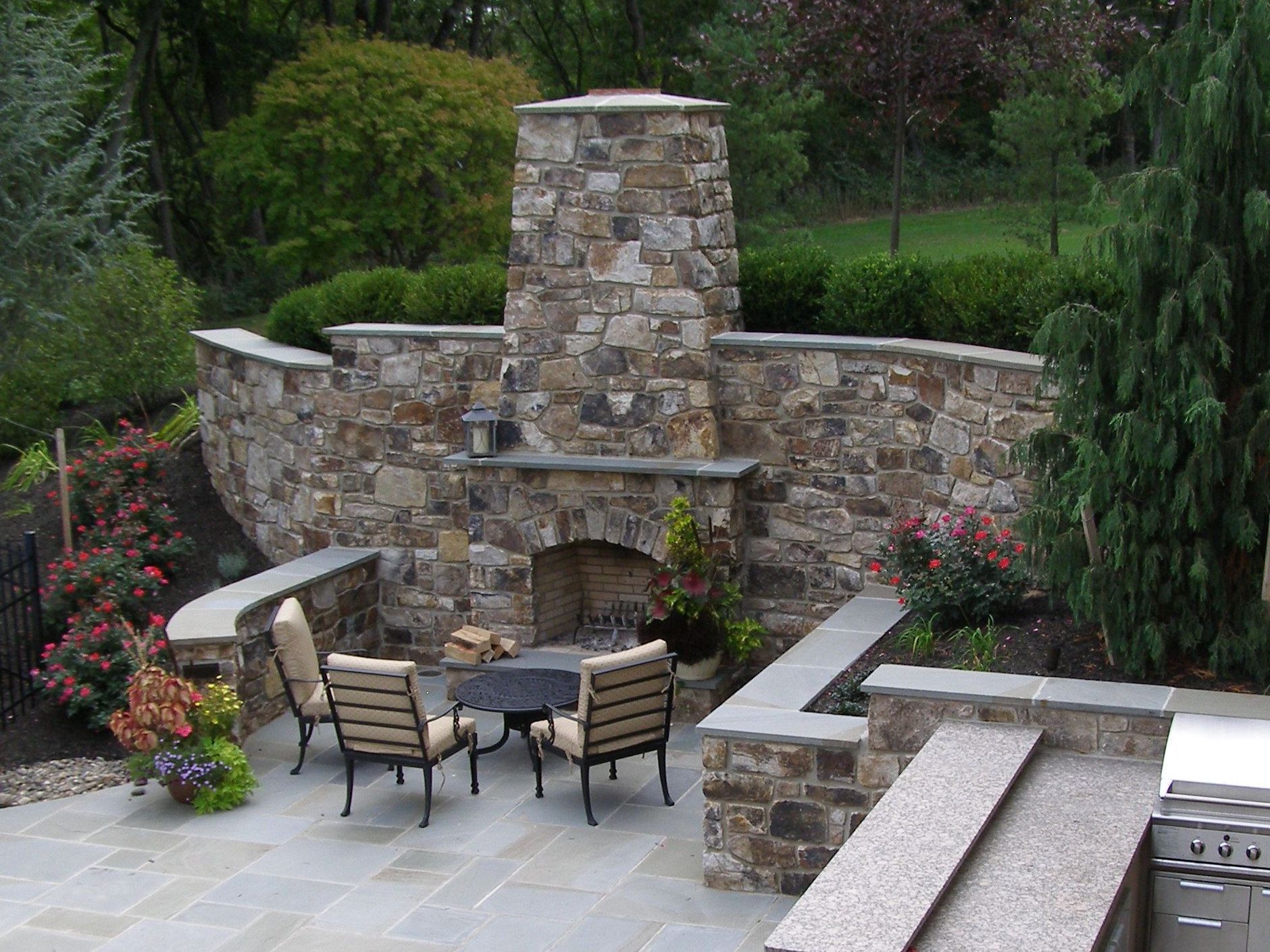 Outdoor fireplace incorporated into high stone wall with 687d0ddd4660e66b f81a3b