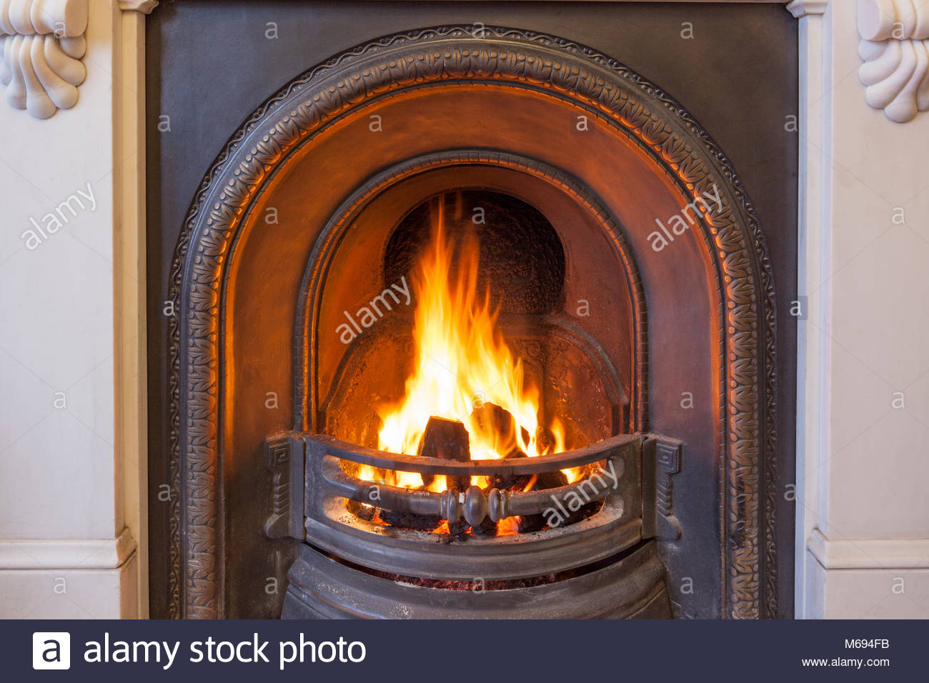 a roaring coal fire in a cast iron grate set in a marble fireplace M694FB