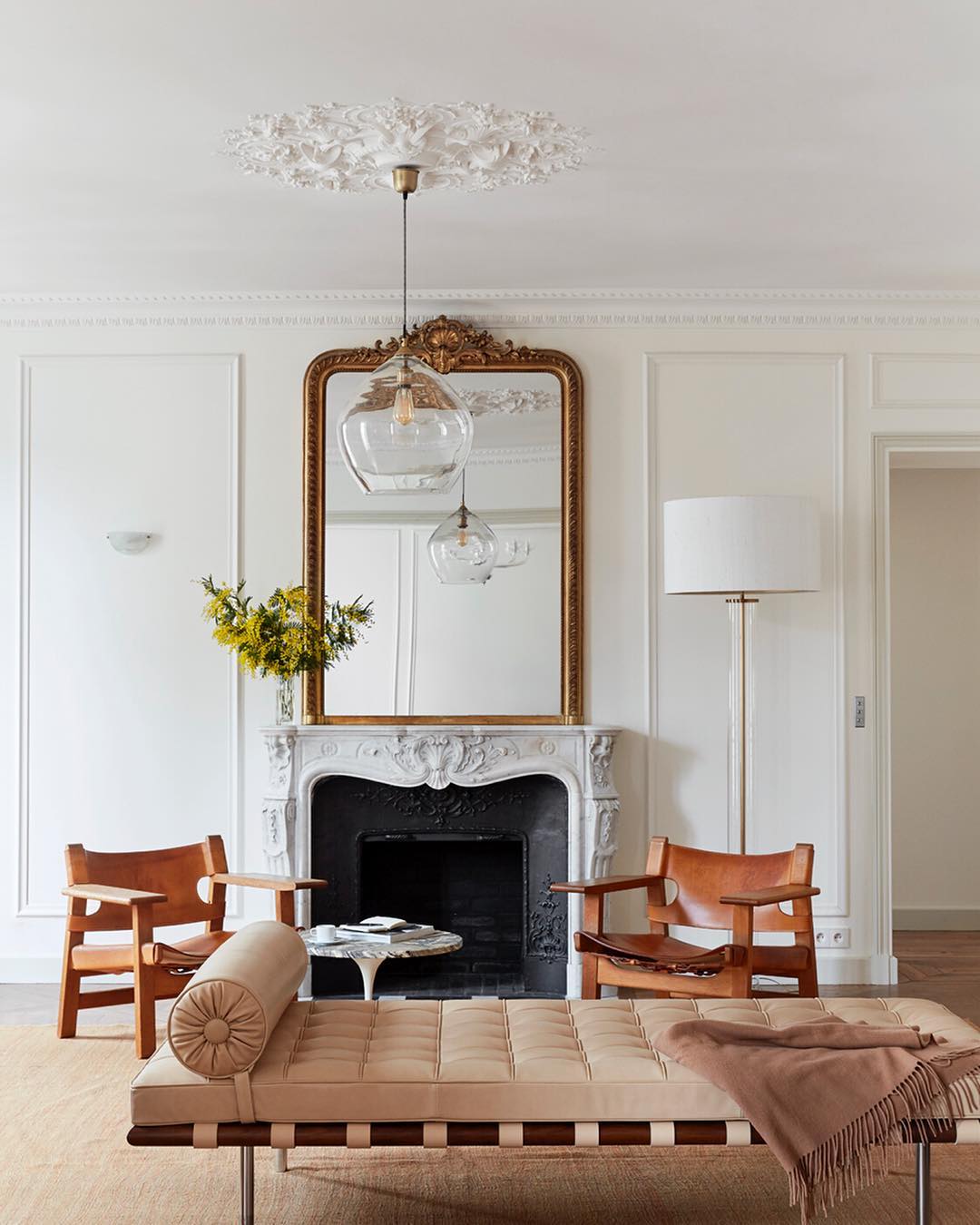 Parisian mirror in Paris apartment with fireplace and beige leather chairs via abkasha